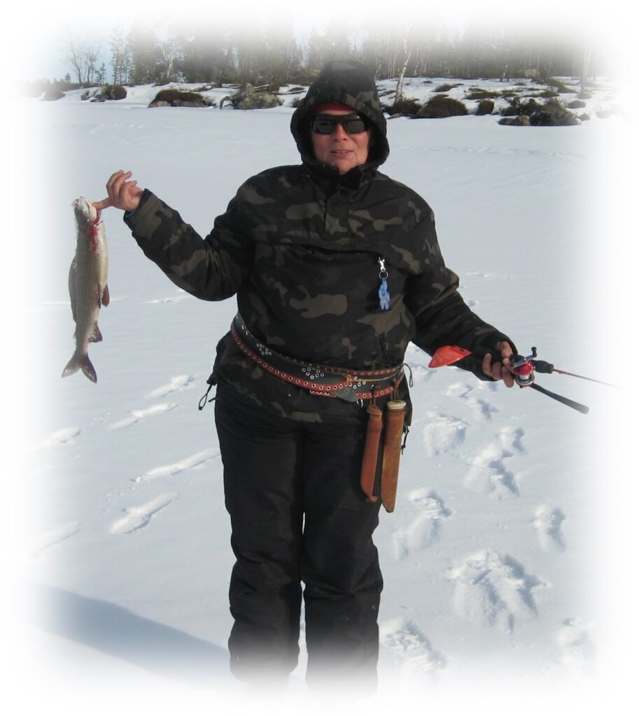 Pilkkijä saaliin kanssa järven jäällä.